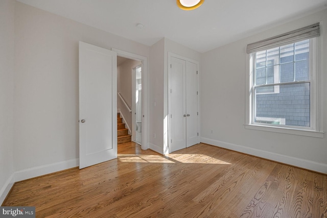 unfurnished bedroom with a closet, baseboards, and wood finished floors