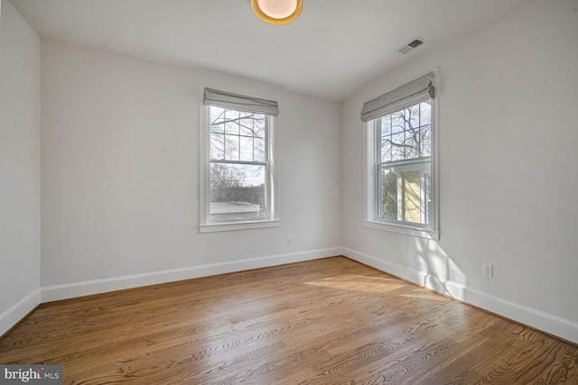 unfurnished room with visible vents, baseboards, and wood finished floors