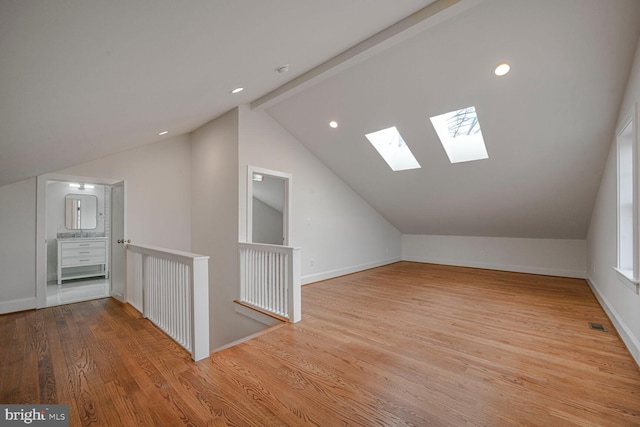 additional living space with vaulted ceiling with beams, visible vents, baseboards, and wood finished floors