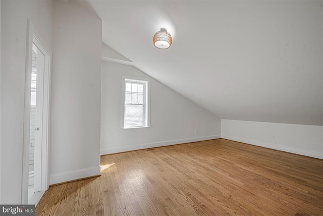 bonus room featuring vaulted ceiling, light wood-style flooring, and baseboards