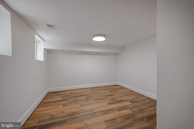 below grade area with visible vents, baseboards, and wood finished floors