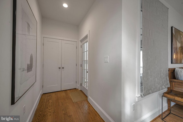 hallway featuring baseboards, wood finished floors, and recessed lighting