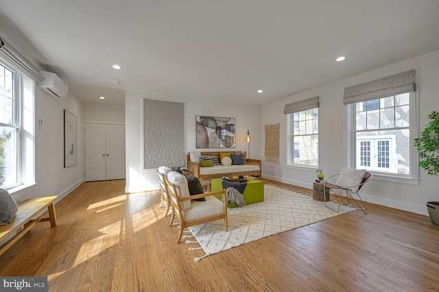 sitting room with a wall unit AC, baseboards, wood finished floors, and recessed lighting