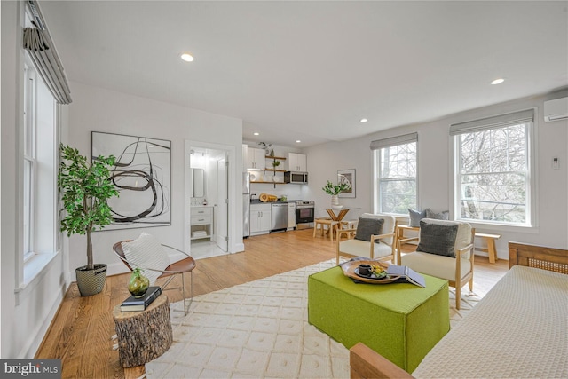 living area with recessed lighting, light wood finished floors, and a wall mounted AC