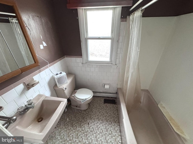 full bathroom with a baseboard radiator, sink, tile walls, toilet, and shower / bath combo with shower curtain