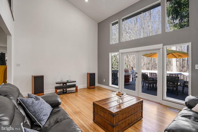 living room featuring hardwood / wood-style floors, high vaulted ceiling, and french doors