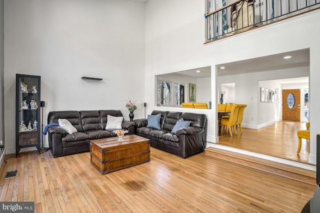 living room with a towering ceiling and light hardwood / wood-style flooring