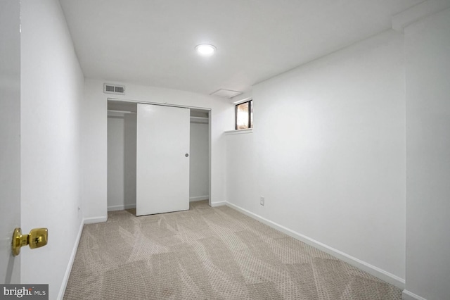 unfurnished bedroom featuring light colored carpet and a closet