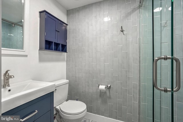 bathroom featuring vanity, a shower with door, and toilet