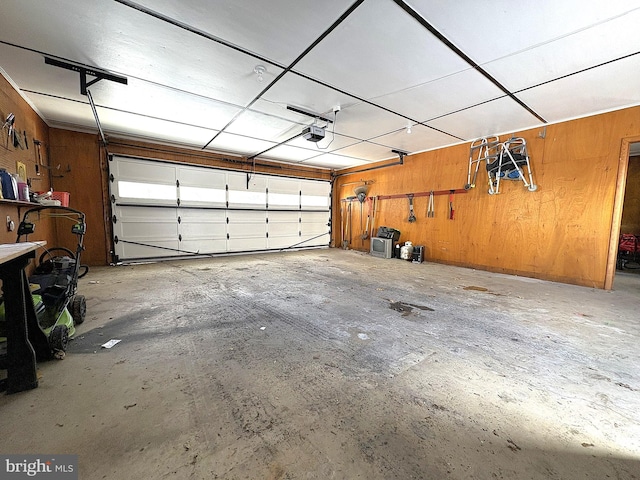 garage featuring a garage door opener and wooden walls