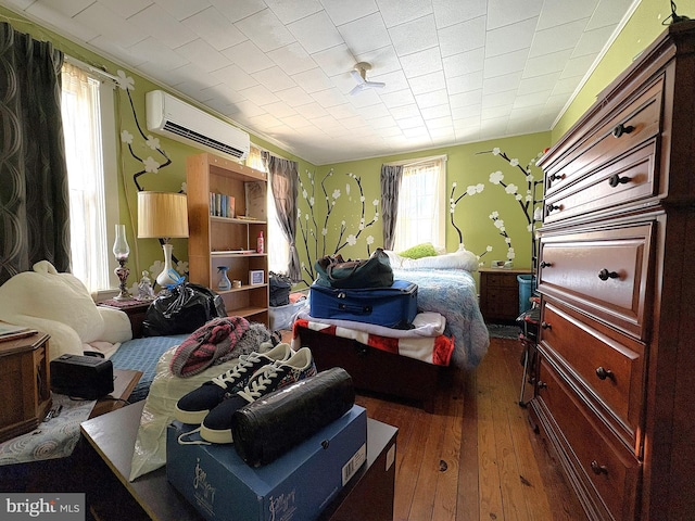 bedroom with dark hardwood / wood-style floors and an AC wall unit