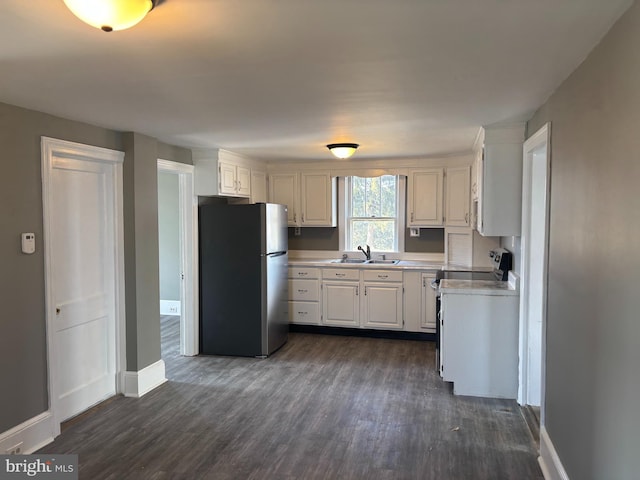 kitchen featuring dark hardwood / wood-style floors, white electric stove, white cabinetry, sink, and stainless steel fridge