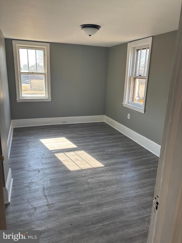 empty room featuring dark wood-type flooring and plenty of natural light