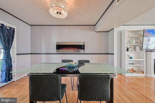 dining area with built in shelves, ornamental molding, a chandelier, and light hardwood / wood-style flooring