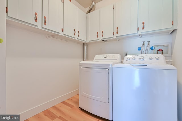 washroom featuring cabinets, separate washer and dryer, and light hardwood / wood-style flooring