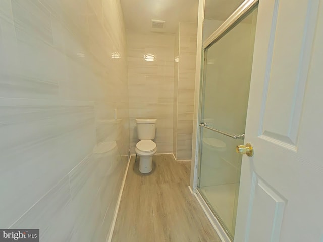 bathroom featuring hardwood / wood-style floors, tile walls, an enclosed shower, and toilet