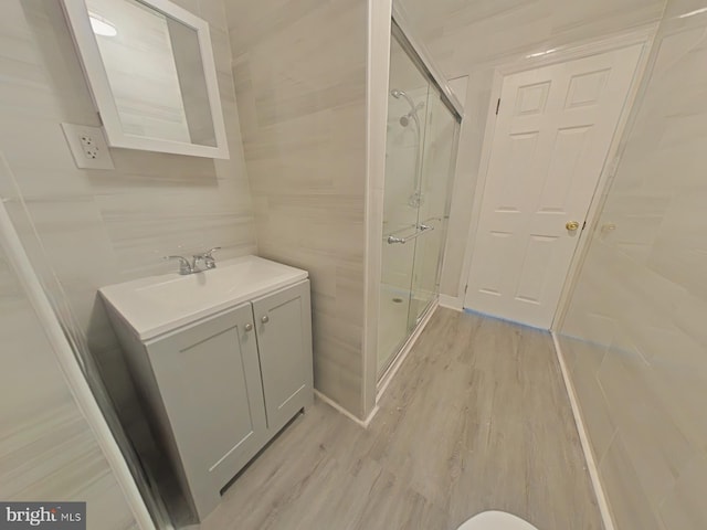 bathroom featuring hardwood / wood-style flooring, vanity, and a shower with shower door