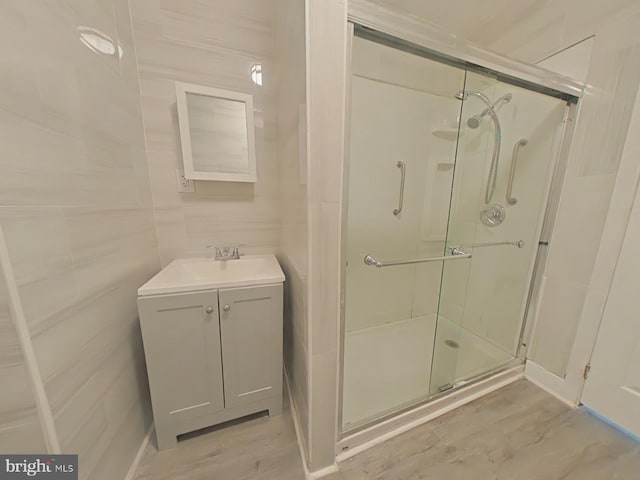 bathroom featuring hardwood / wood-style flooring, vanity, tile walls, and a shower with shower door