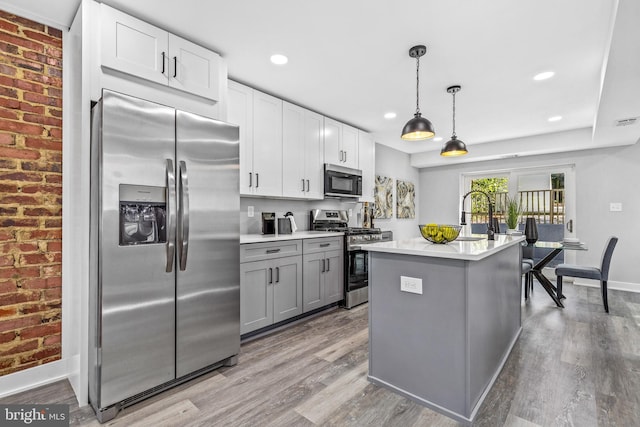 kitchen with white cabinetry, appliances with stainless steel finishes, gray cabinetry, and decorative light fixtures