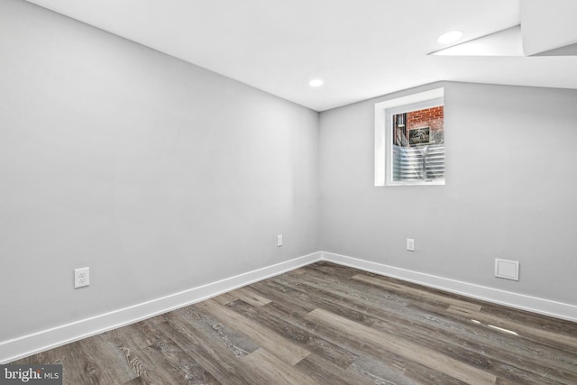 unfurnished room with dark wood-type flooring and lofted ceiling