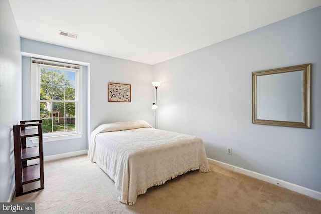 bedroom with baseboards, visible vents, and light colored carpet