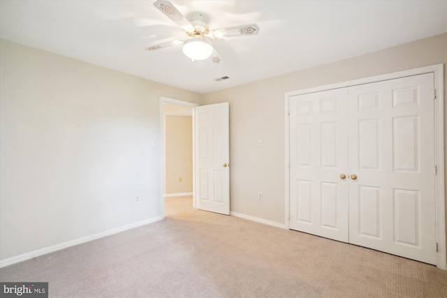 unfurnished bedroom featuring ceiling fan, light colored carpet, visible vents, baseboards, and a closet