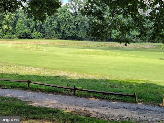 view of home's community featuring view of golf course, fence, and a lawn