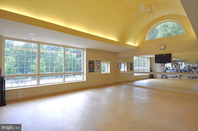 unfurnished living room with baseboards, visible vents, a towering ceiling, and a healthy amount of sunlight