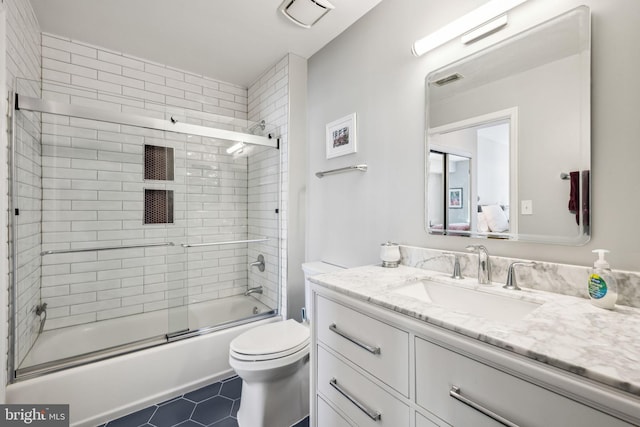 full bath featuring bath / shower combo with glass door, visible vents, toilet, vanity, and tile patterned flooring