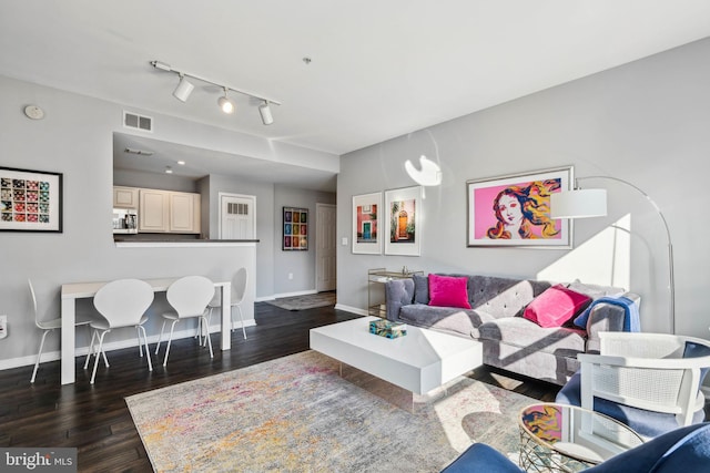 living area with dark wood-style floors, track lighting, visible vents, and baseboards