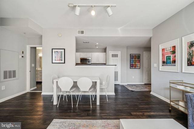 dining area featuring dark wood-type flooring, visible vents, and baseboards