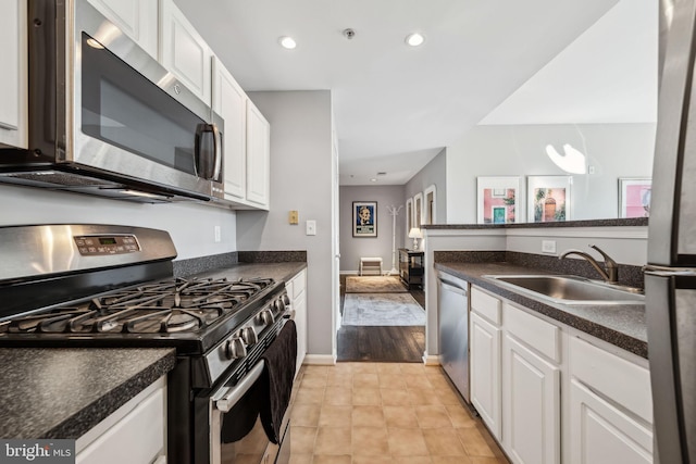 kitchen featuring dark countertops, appliances with stainless steel finishes, white cabinets, and a sink