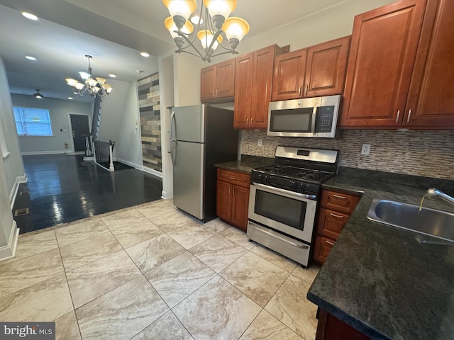 kitchen featuring appliances with stainless steel finishes, pendant lighting, tasteful backsplash, sink, and an inviting chandelier