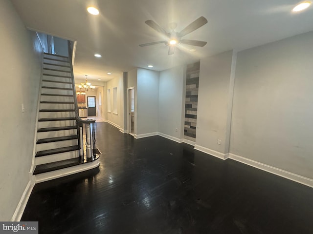 basement with dark hardwood / wood-style flooring and ceiling fan with notable chandelier