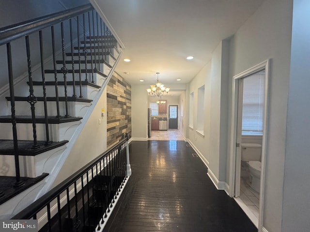 hall featuring wood-type flooring and an inviting chandelier