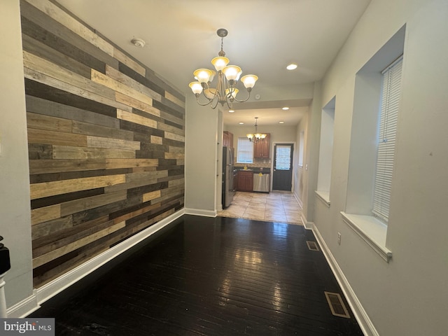 corridor featuring wood walls, light hardwood / wood-style floors, and a notable chandelier