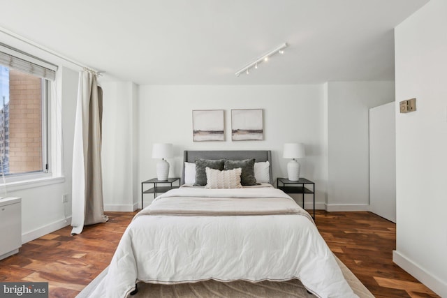 bedroom with track lighting and dark hardwood / wood-style flooring