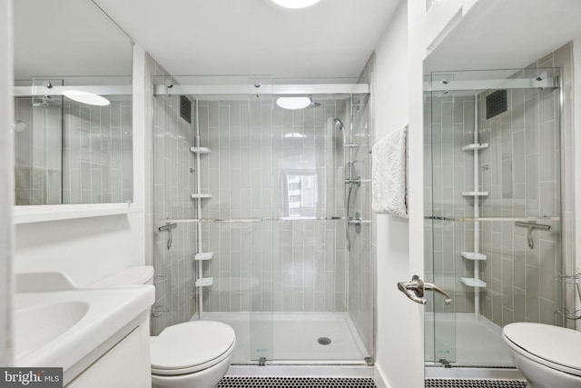 bathroom with vanity, toilet, a shower with door, and a baseboard heating unit