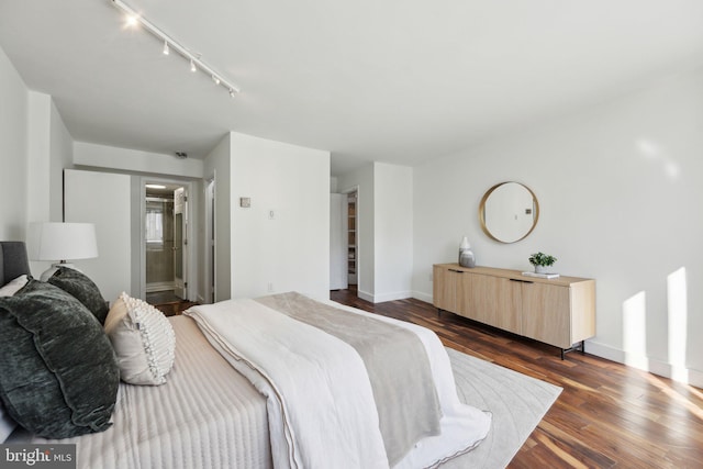 bedroom featuring connected bathroom, dark hardwood / wood-style floors, and rail lighting