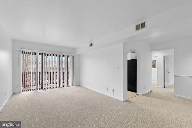 spare room with baseboards, visible vents, and light carpet