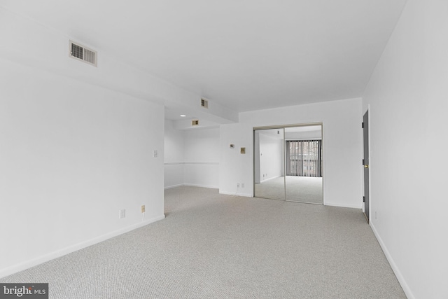 empty room with baseboards, visible vents, and light carpet