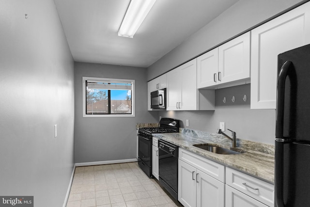 kitchen featuring a sink, light stone counters, baseboards, white cabinets, and black appliances