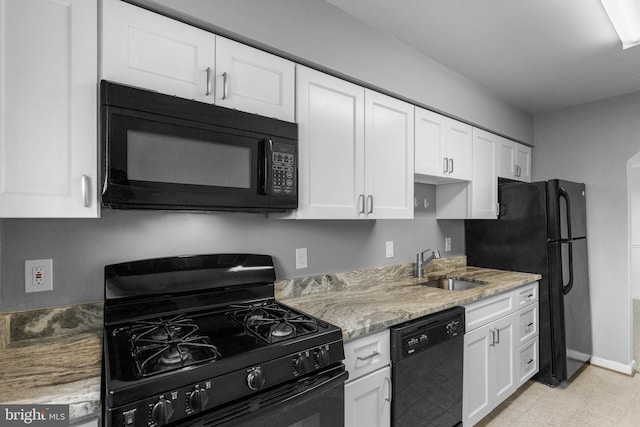 kitchen featuring baseboards, light stone countertops, a sink, black appliances, and white cabinetry