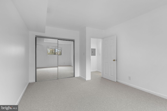 unfurnished bedroom featuring baseboards, a closet, electric panel, and carpet