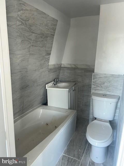 bathroom featuring tile walls, sink, toilet, and a tub to relax in