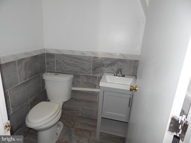 bathroom with vanity, tile walls, and toilet