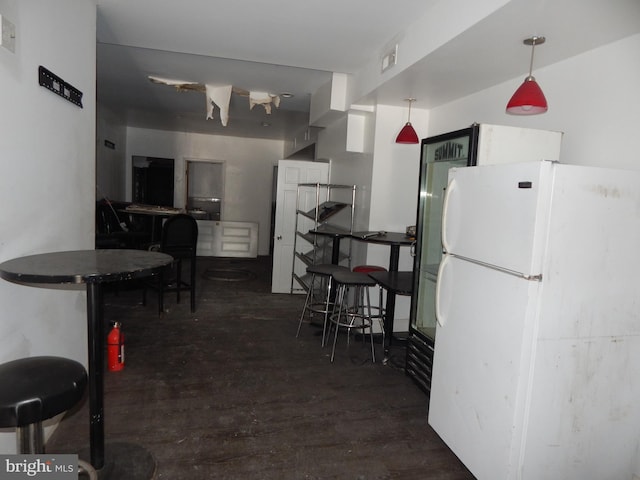 kitchen featuring dark hardwood / wood-style flooring, hanging light fixtures, and white refrigerator