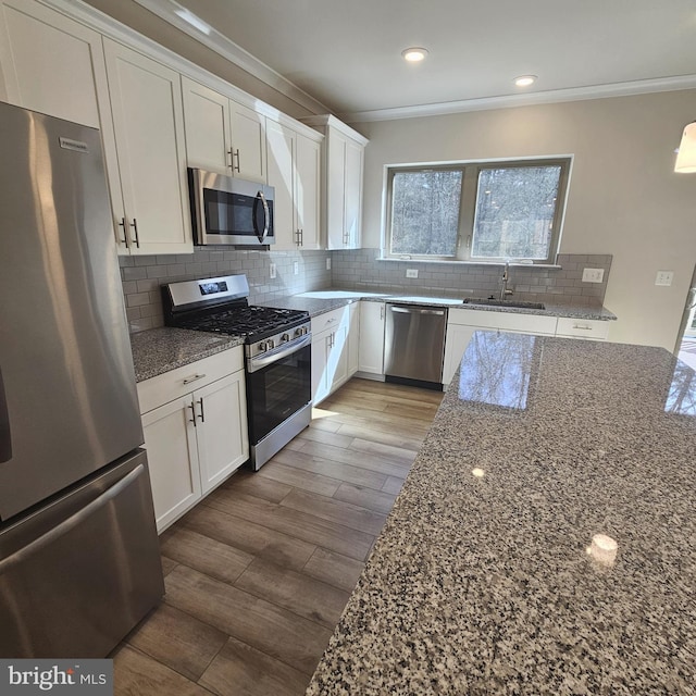 kitchen featuring sink, white cabinetry, dark stone countertops, stainless steel appliances, and decorative backsplash