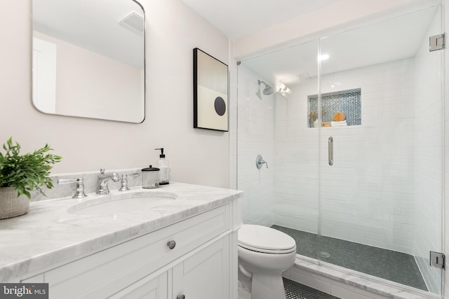 bathroom featuring toilet, vanity, and a shower with shower door