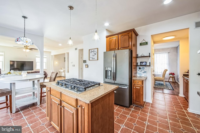 kitchen with stainless steel appliances, a kitchen island, hanging light fixtures, and ceiling fan